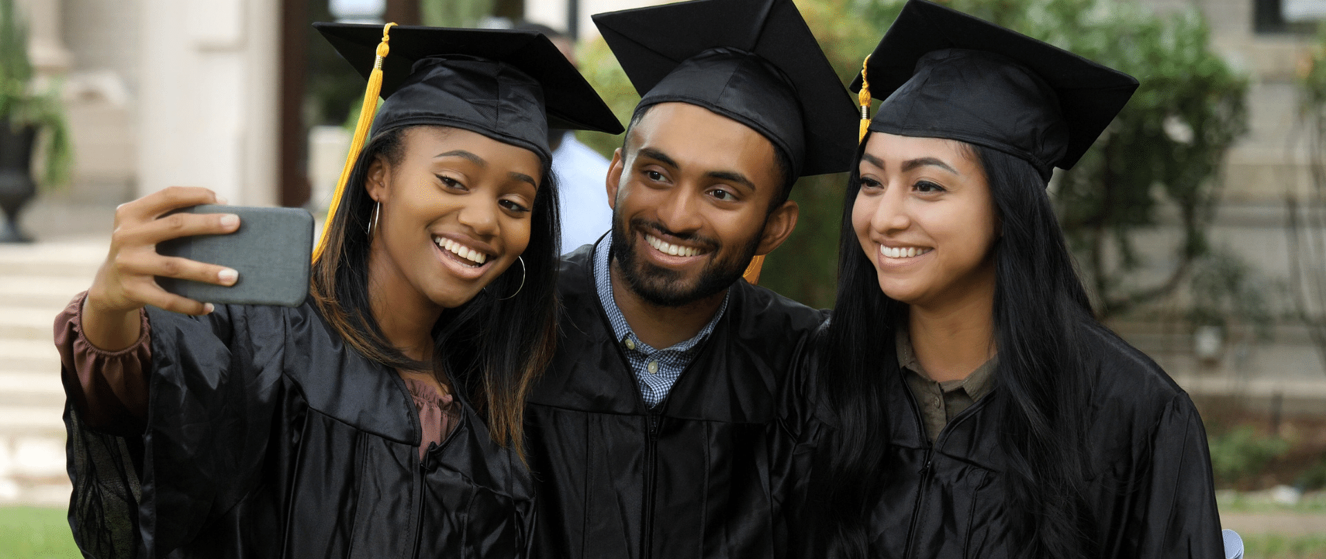 Image of 3 smiling young adults from foster care wearing college graduation caps and gowns smiling for a selfie Image of 3 smiling young adults from foster care wearing college graduation caps and gowns smiling for a selfie