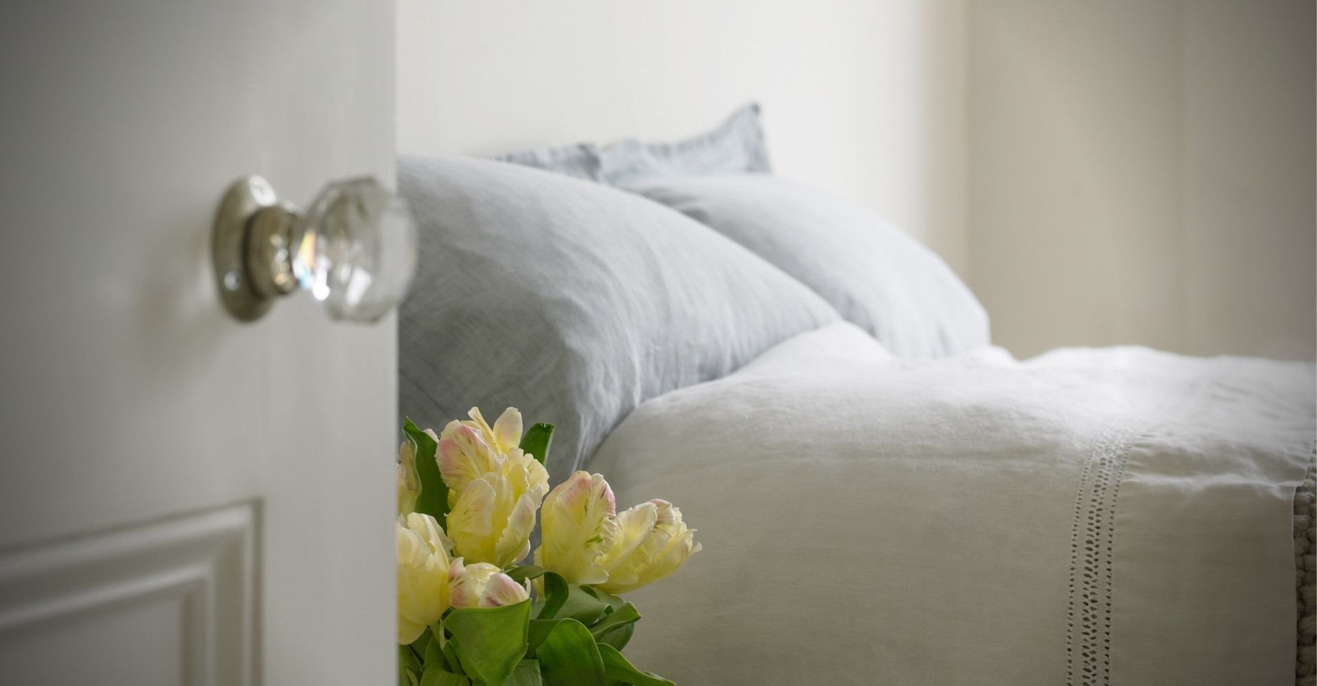 host homes host home bed in white linens and a vase of yellow flowers