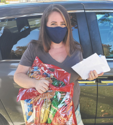 Christina Dronen holding popcornopolis popcorn bags and cards to take when Delivering Thanksgiving Dinners