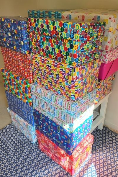 brightly wrapped birthday celebration boxes stacked 5 high and 2 deep on a blue rug
