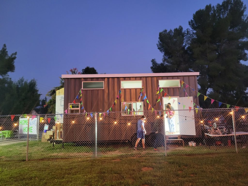 Finally Family Homes' dark gray Tiny Home on Wheels in Santa Clarita for foster youth at risk of homelessness - decorated by lights. 